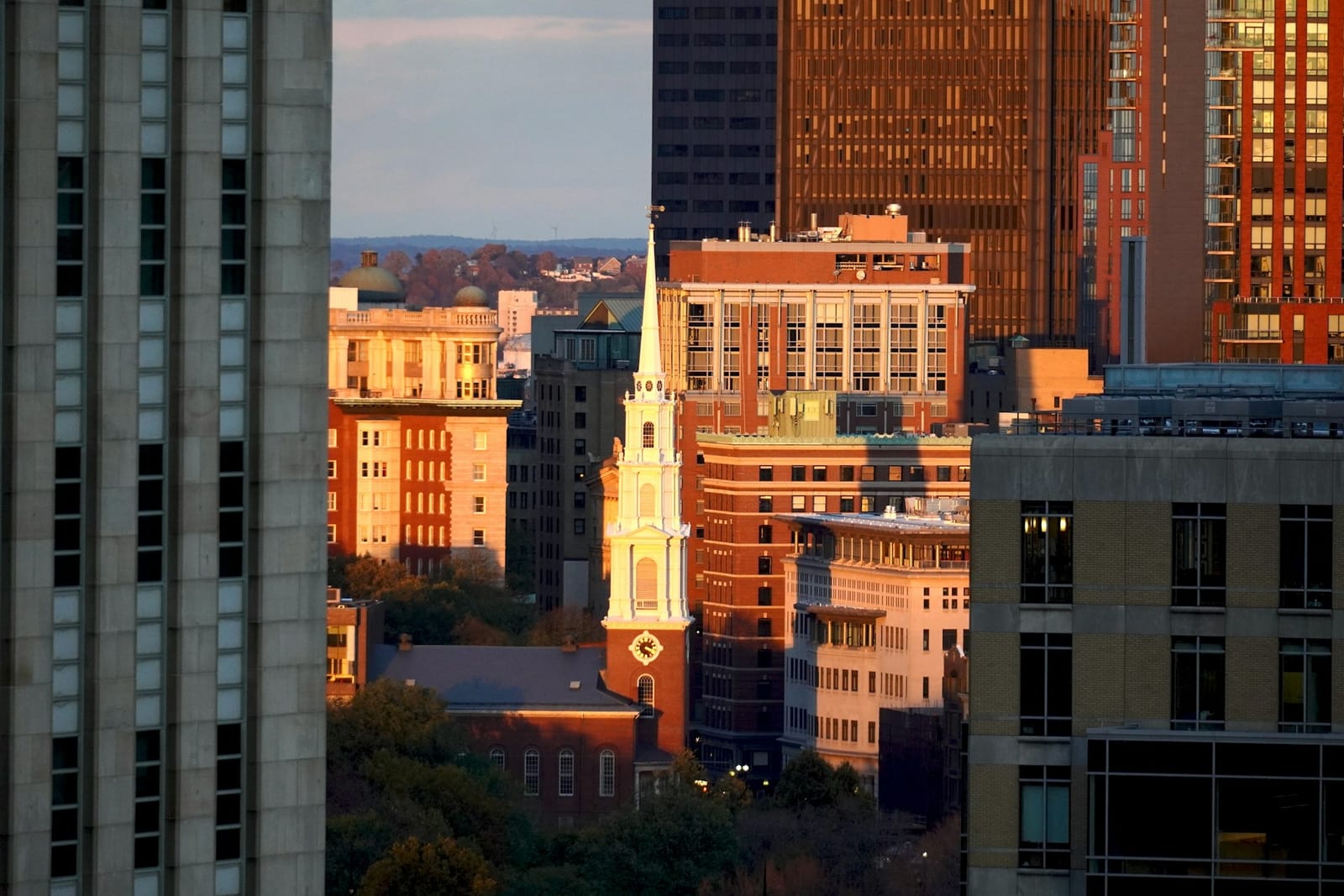 A church steeple against the Boston skyline at golden hour
