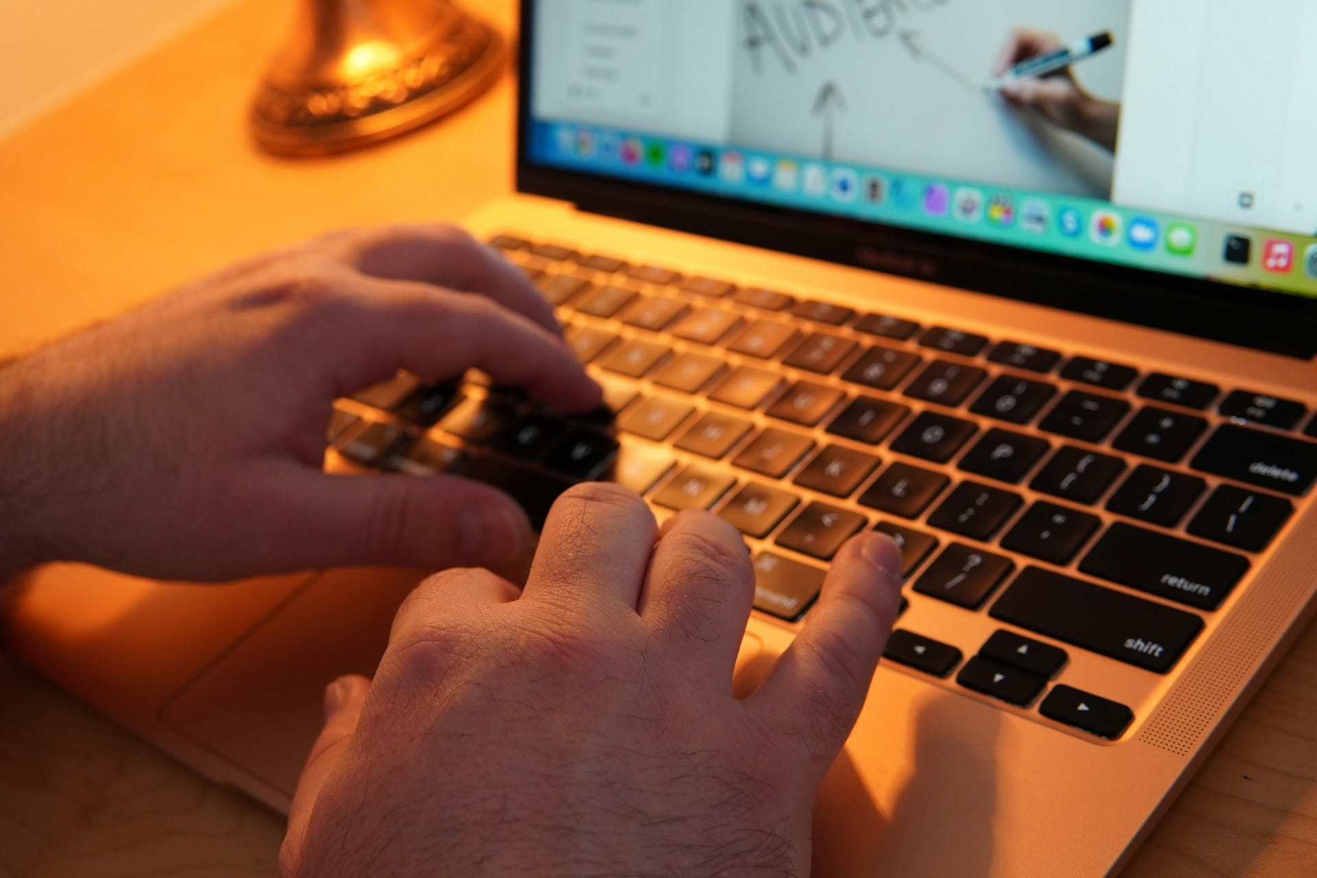 Hands typing on a laptop in warm evening light